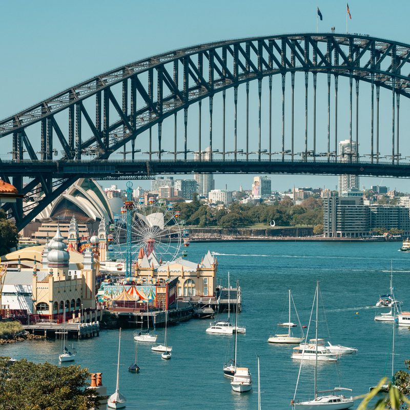 Sydney Harbour Bridge above Luna Park, with sailboats moored in the harbour below.